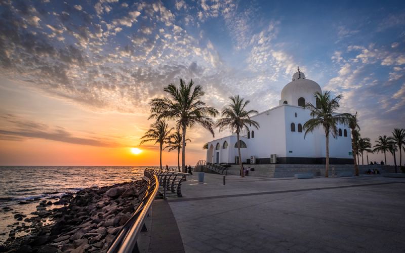 Beautiful seaside mosque with palm trees under a golden sunset in saudi arabia